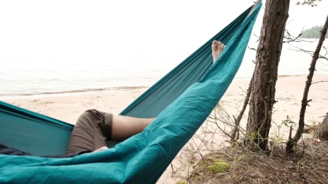 Hombre-caucásico-joven-Descansando-tumbado-en-la-hamaca-azul-al-aire-libre-cerca-del-lago.