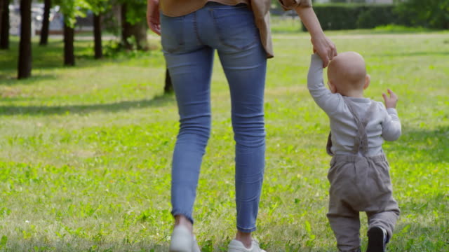 Madre-y-bebé-sostener-las-manos-y-caminando-en-el-Parque