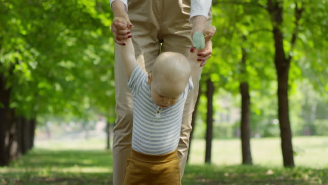Woman-Teaching-Baby-Boy-to-Walk-Outdoors
