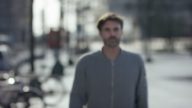 Middle-aged-attractive-man-walking-towards-the-camera-in-urban-city,-place-for-text