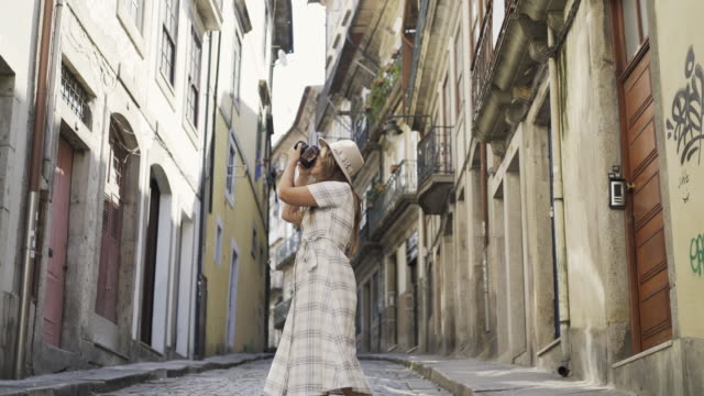 Woman-in-dress-and-hat-shooting-buildings-on-street