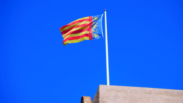 Flag-of-Valencia-(Spain)-flying-over-the-building-against-the-blue-sky