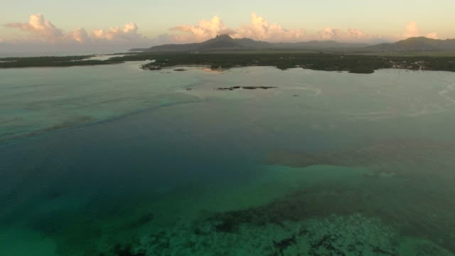 Aerial-view-of-ocean-blue-water-with-waves,-corals-and-water-plants,-camera-moving-to-coast,-Mauritius-Island