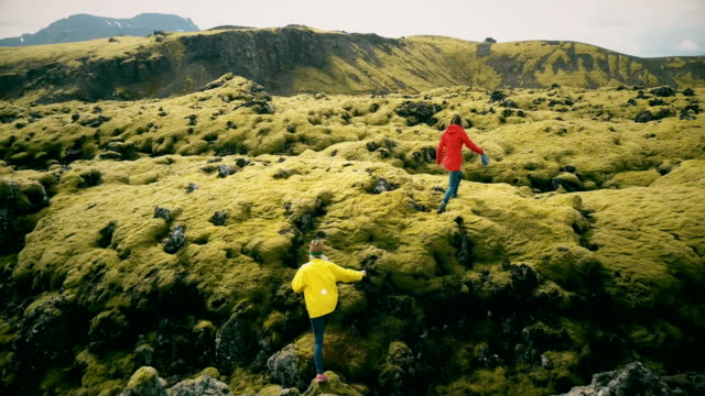 Luftaufnahme-der-zwei-Frau-Wandern,-Wandern-auf-dem-Lavafeld-in-Island.-Touristen-auf-dem-weichen-Moos-nach-unten-fällt.