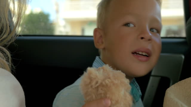 Junge-mit-Plüschtier-auf-dem-Auto-Rücksitz