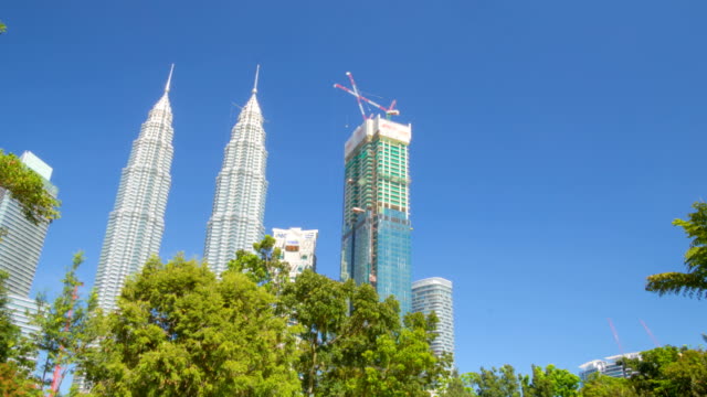 Las-Torres-Petronas-en-Kuala-Lumpur,-vista-desde-el-parque.-Timelapse-de-movimiento