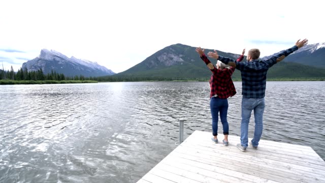 Pareja-joven-en-el-lago-en-Canadá,-brazos-extendidos-por-la-libertad