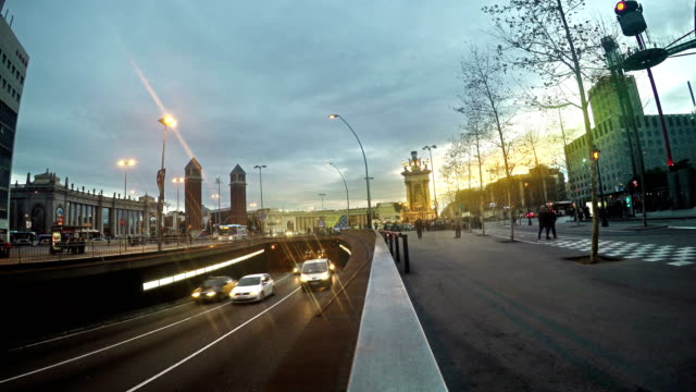 Trafic-out-of-tunnel-on-Placa-Espanya-at-sunset,-Barcelona,-Spain