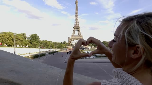 Mujer-joven-haciendo-forma-de-corazón-en-la-Torre-Eiffel,-amantes-de-la-ciudad-Francia