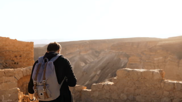 Male-tourist-photographs-amazing-mountain-scenery.-Young-man-with-backpack-takes-photos.-Freedom.-Masada-Israel-4K