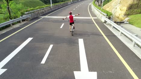 Aerial-view-of-experienced-woman-hands-free-cycling-riding-bike-on-highway-road