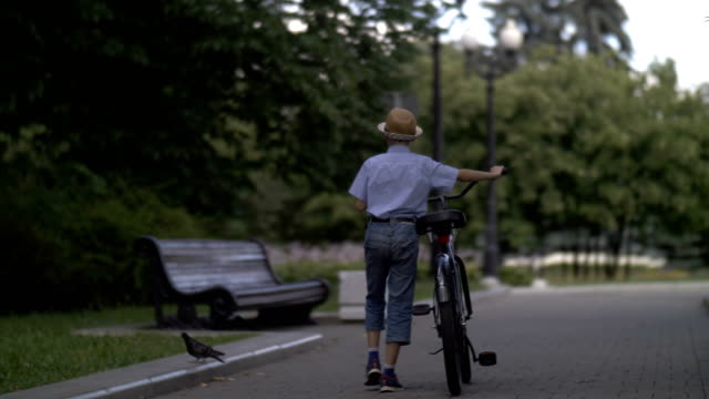 niño-está-caminando-con-una-bicicleta-en-la-ciudad,-al-aire-libre