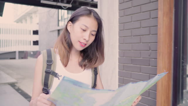 Cheerful-beautiful-young-Asian-backpacker-woman-direction-and-looking-on-location-map-while-traveling-at-Chinatown-in-Beijing,-China.-Lifestyle-backpack-tourist-travel-holiday-concept.