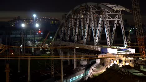 Der-Bau-einer-Stahlbrücke-und-Nacht-Durchfahrt-von-Zügen-auf-einem-Eisenbahnknotenpunkt