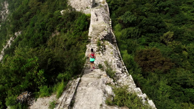 vista-aérea-de-corredor-de-trail-de-mujer-fitness-joven-corriendo-encima-de-gran-muralla