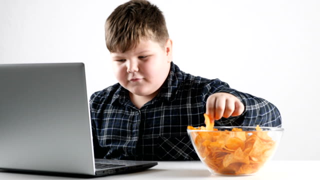 Young-fat-boy-eats-chips-and-and-plays-on-a-laptop-50-fps