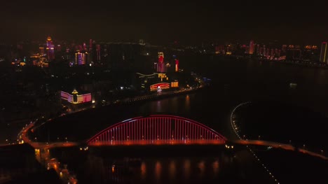 night-illuminated-wuhan-city-riverside-hotel-and-bridge-aerial-panorama-4k-china