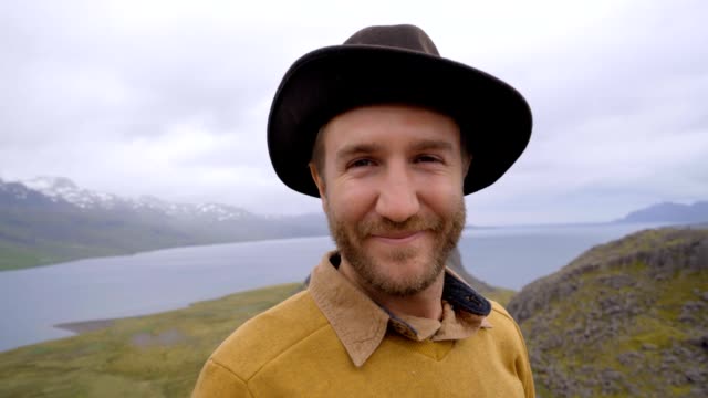 Slow-motion-video-Portrait-of-young-man-in-Iceland-near-lake-and-mountains