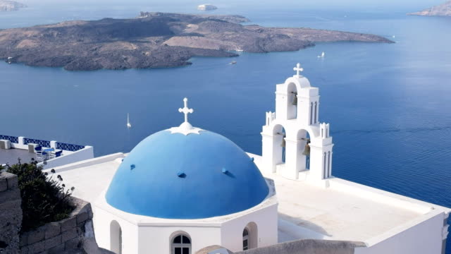 wide-shot-of-a-blue-church-dome-and-three-bells-in-fira,-santorini