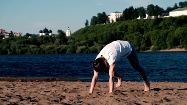 Woman-doing-yoga-on-the-beach-by-the-river-in-the-city.-Beautiful-view-in-Urdhva-Mukha-shvanasana-pose.