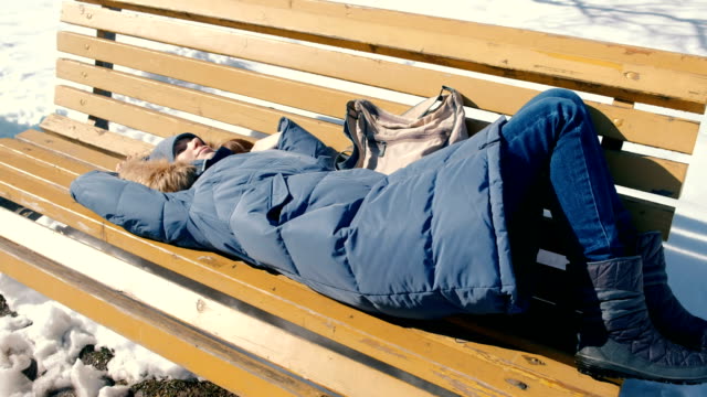Joven-cansada-se-duerme-en-el-parque-en-un-banco-en-el-invierno.
