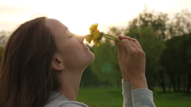 Woman-smells-field-flowers,-face-and-dandelions-close-up