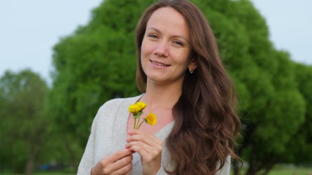 Smiling-woman-with-small-dandelions-in-hands