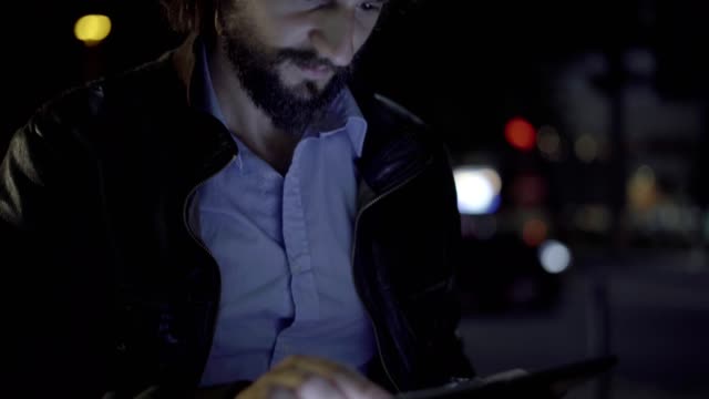 Confident-teleworker-using-digital-tablet-in-night-city