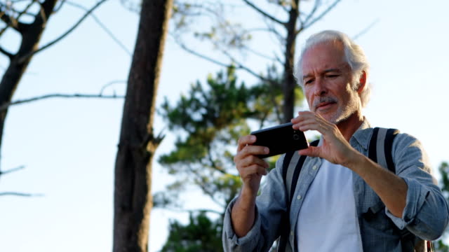 Senior-hombre-clic-en-fotos-con-el-teléfono-móvil-en-el-campo-4k