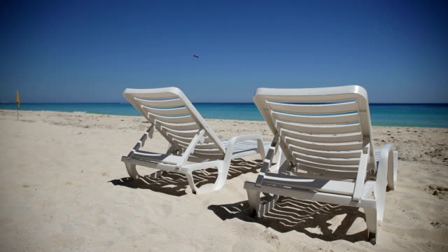 Las-sillas-reclinables-en-la-playa-tropical-calmo