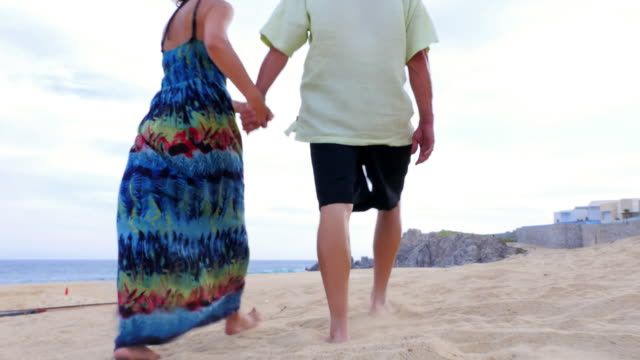 Eine-ältere-paar-Hände-halten,-zu-Fuß-am-Strand