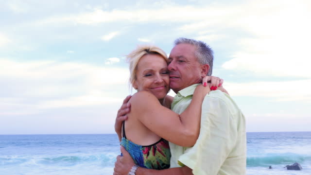 Porträt-von-ein-älteres-Paar-umarmen-und-Lächeln-am-Strand