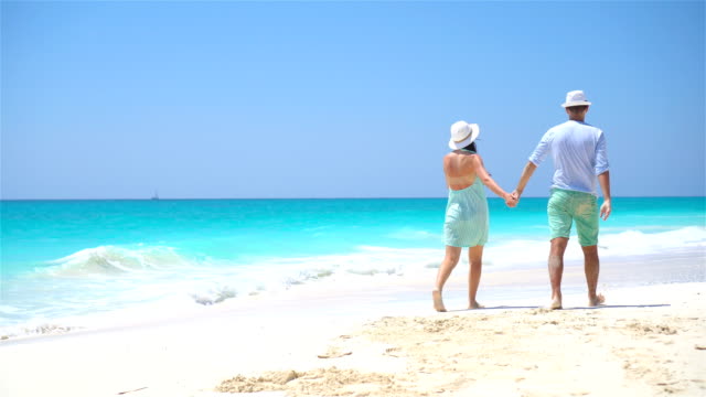 Young-couple-on-white-beach-during-summer-vacation.-Happy-lovers-enjoy-their-honeymoon.
