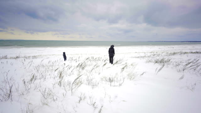 mother-and-kid-walking-on-beach-ontario-canada-in-winter-with-snow