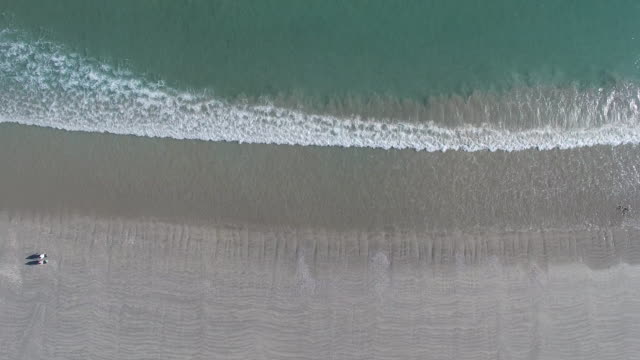 Aerial-Shot-of-Wave-Break-and-Beach-Walkers
