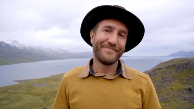 Slow-motion-video-retrato-de-hombre-joven-en-Islandia-cerca-de-lago-y-montañas