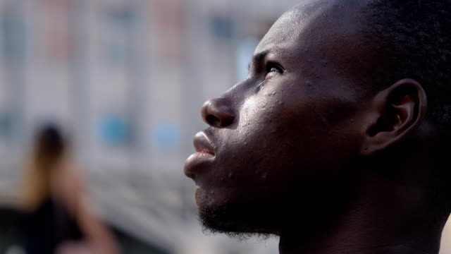 Perfil-del-hombre-africano-negro-joven-pensativo-mirando-para-arriba-al-aire-libre