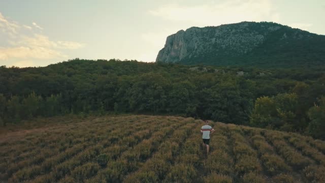 junger-Mann-lässig-zu-Fuß-auf-einem-Berg-Feld-am-Abend-während-der-Sommersaison