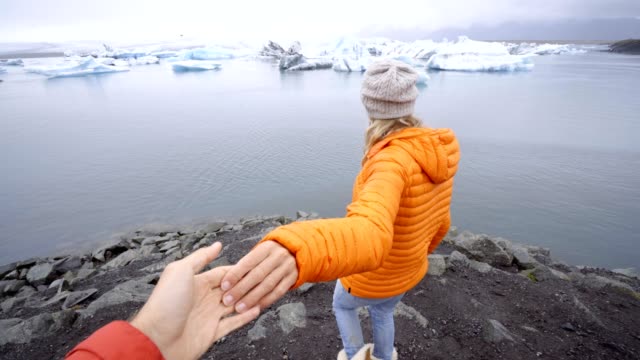 Follow-me-to-concept,-young-woman-leading-boyfriend-to-glacier-lagoon-in-Iceland