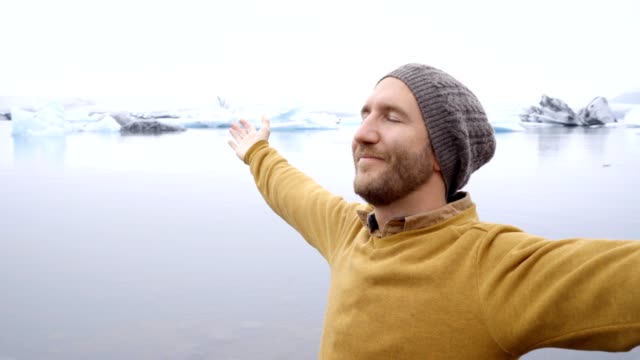 Hombre-joven-de-brazos-extendidos-en-la-laguna-de-glaciar-en-Islandia