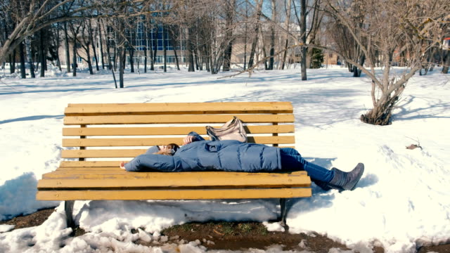 Müde-Mädchen-schläft-im-Park-auf-einer-Bank-im-Winter.