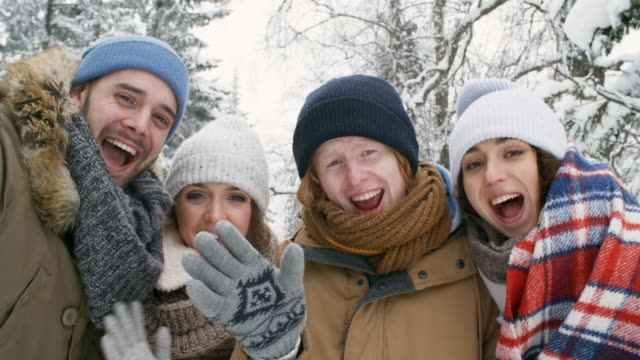 Happy-Friends-Waving-at-Camera-Outdoors-at-Winter-Day