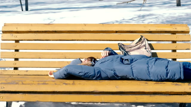Tired-young-woman-sleeps-in-the-Park-on-a-bench-in-the-winter.