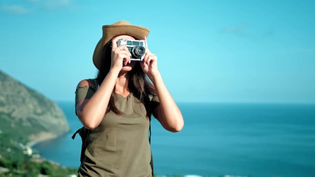Female-professional-photographer-taking-picture-using-vintage-film-camera-on-peak-of-mountain