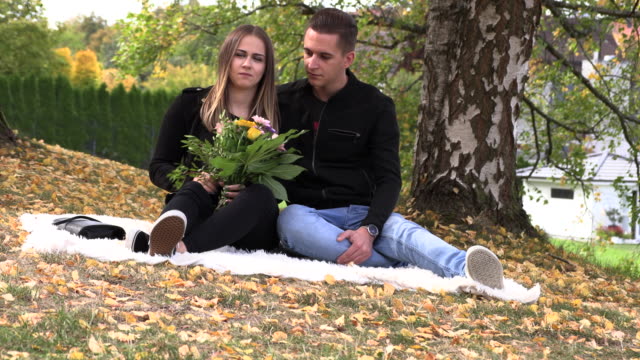 Una-joven-pareja-se-asienta-sobre-un-cubrecama-blanco-en-el-Parque-otoño