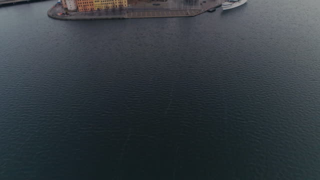 Drohne-Schuss-von-Stockholm-Stadtzentrum-entfernt.-Luftaufnahme-fliegen-über-Wasser-und-Kamera-Tilt-auf-Altstadt-Gebäude-und-Türme.-Hauptstadt-von-Schweden