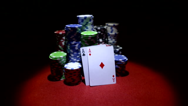 Teo-Asse-und-Stapel-Chips-auf-roten-Casinotisch-Glücksspiel