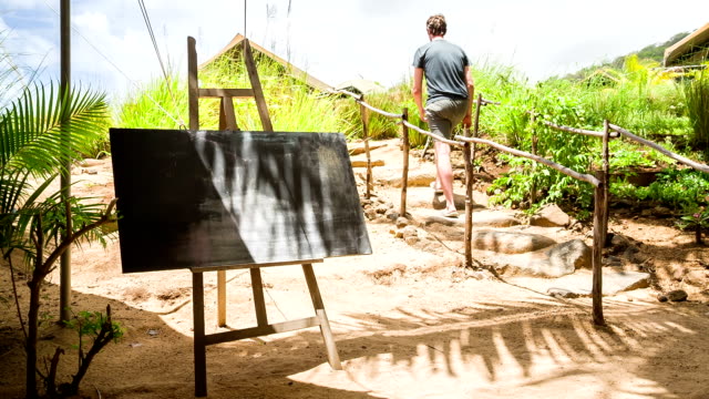 Kreide-board-auf-tropische-Insel-und-die-person-zu-Fuß-durch-Hintergrund