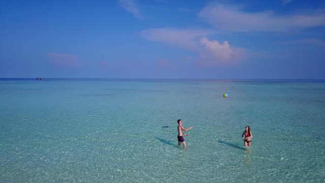 v03817-fliegenden-Drohne-Luftaufnahme-der-Malediven-weißen-Sandstrand-am-sonnigen-tropischen-Inselparadies-mit-Aqua-blau-Himmel-Meer-Wasser-Ozean-4k-2-Personen-junges-Paar-Mann-Frau-Ball-Spaß-zusammen-zu-spielen