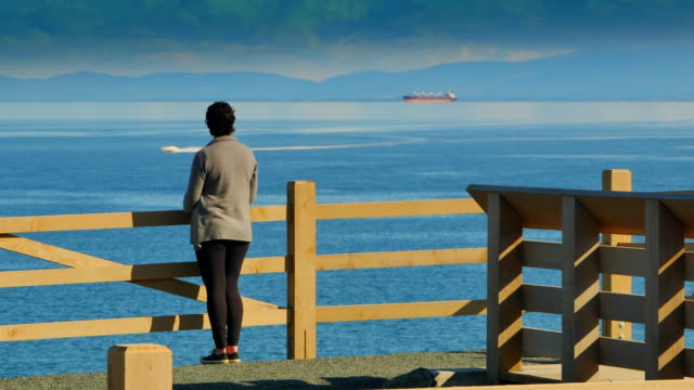 Mujer-viendo-el-barco-en-todo-el-mar-océano,-las-montañas-olímpicas-de-fondo